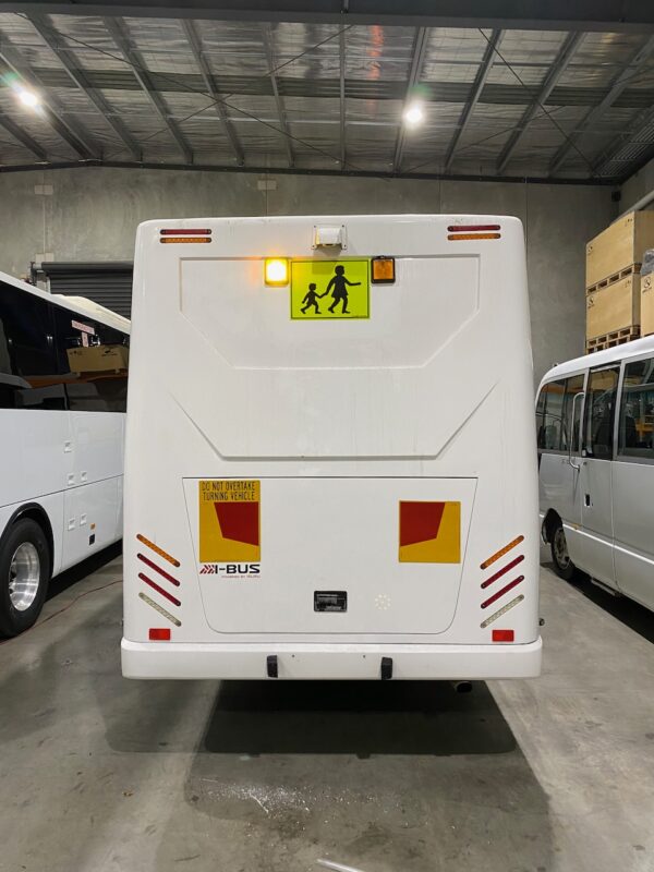 Photo of the rear of a 2024 Isuzu iBus bus with Victorian Safebus SB001A surface mount school bus lights and signage
