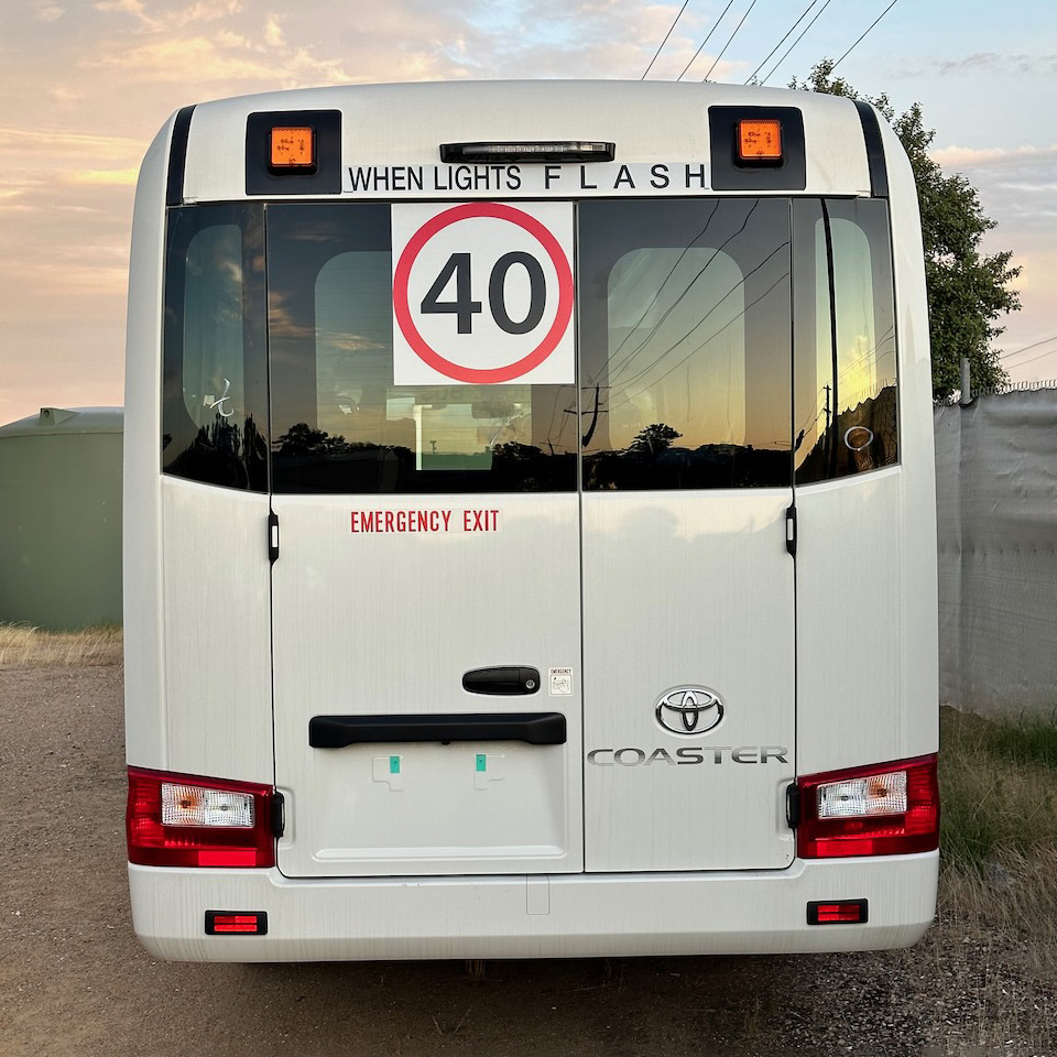 Photo of the rear of a 2024 4th generation B80 Toyota Coaster bus with Safebus SB001A surface mount New South Wales TS150 school bus lights and signage installed
