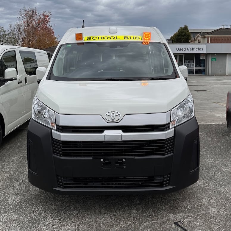 Photo of the front of a 2019 6th generation Toyota HiAce Commuter bus with exterior mount Victorian & Queensland school bus lights and signage installed