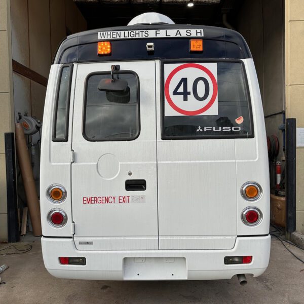 Photo of the back of a Mitsubishi Rosa bus with NSW TS150 school bus lights and signage installed