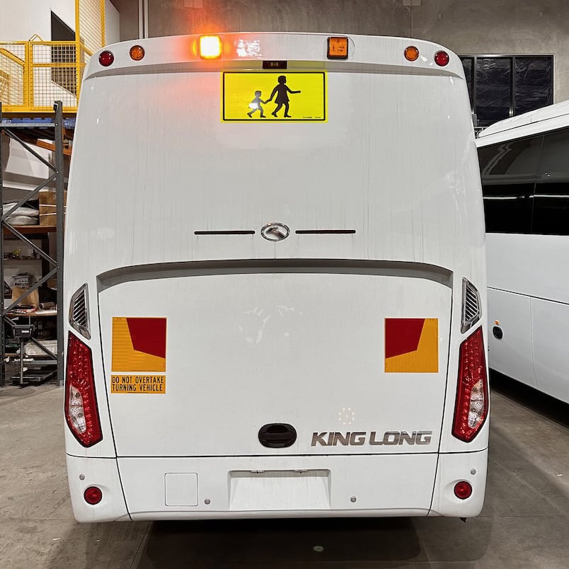 Photo of the rear of a 2024 King Long bus with Victorian Safebus SB001A surface mount school bus lights and signage