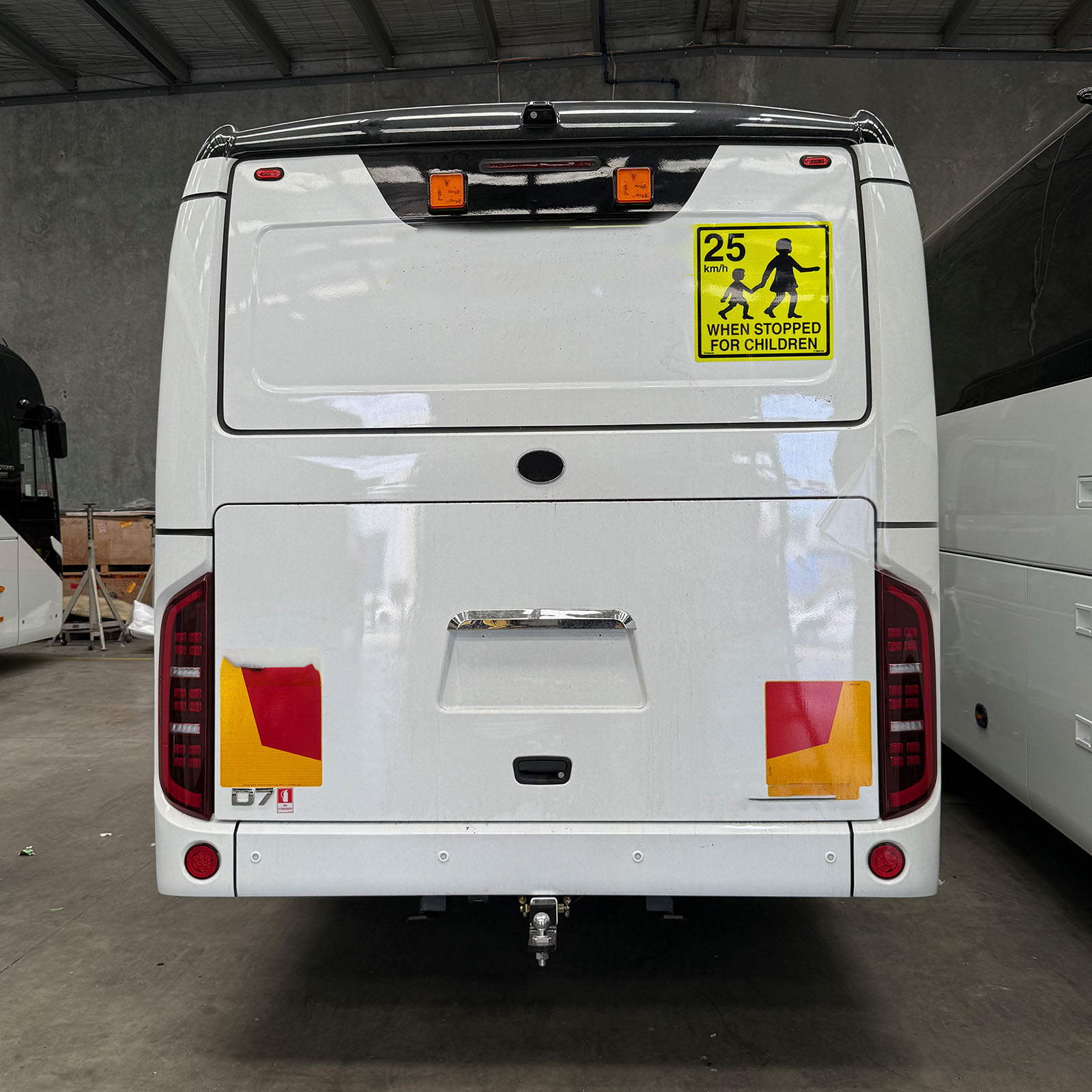 Photo of the rear of a Yutong D7 with SafeBus school bus lights & 25km mother & child when stopped for children signage